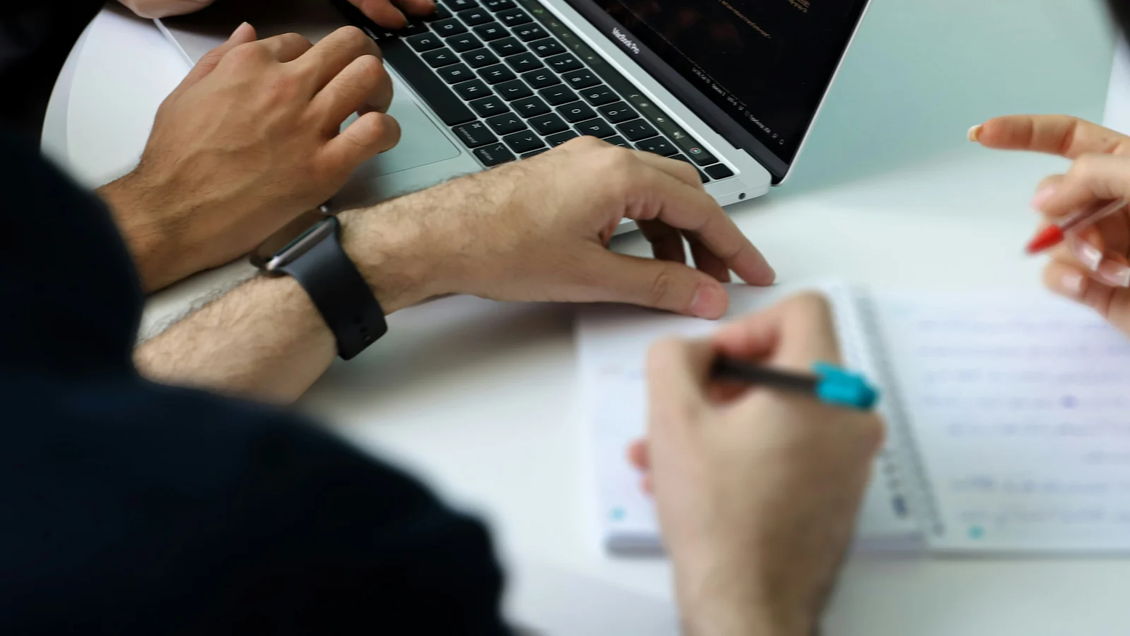 People with notebooks and a laptop at an office table