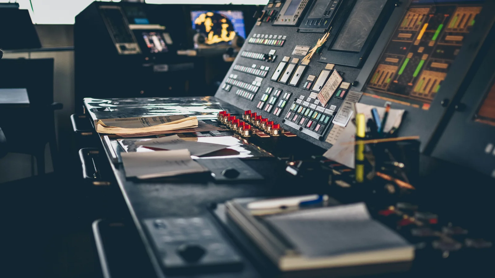 Industrial control desk with buttons, indicator lights, screens and papers